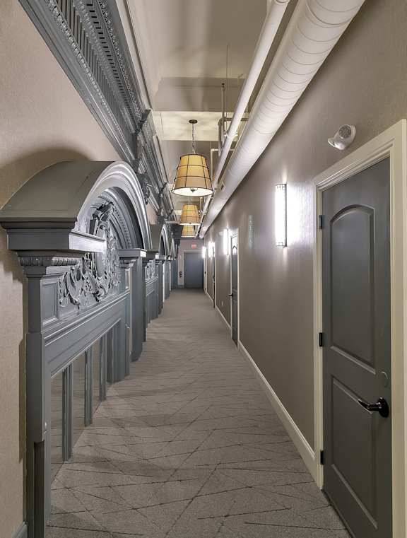 a long hallway with a door and columns on the side at The Knights @ 506 Delaware Apartments, NY 14202