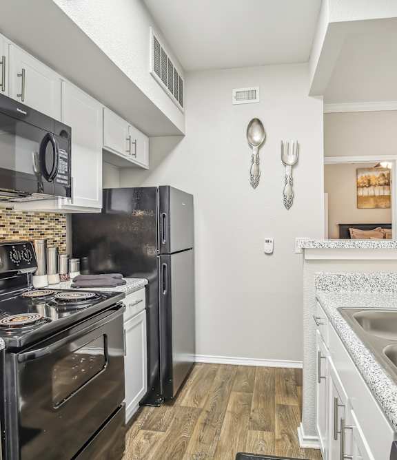 A kitchen with black appliances and white cabinets.