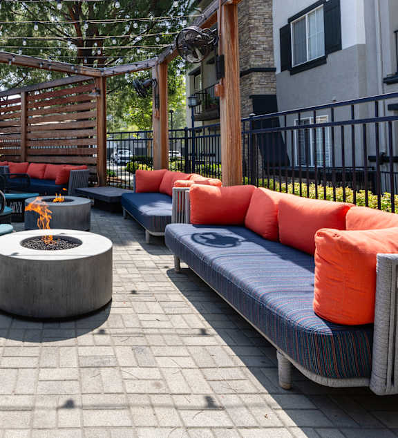 a lounge area with couches and chairs around a fire pit