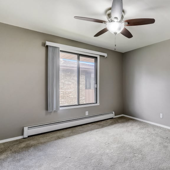 an empty room with a ceiling fan and a window