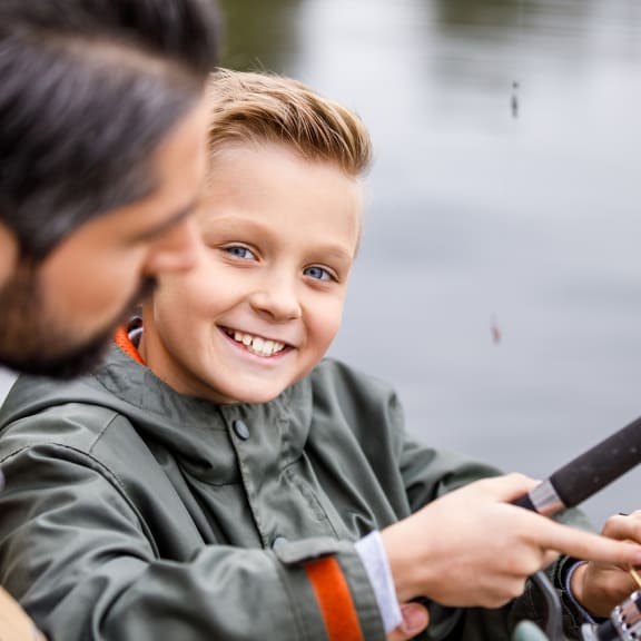 a young boy holding a fishing rod and smiling at the camera