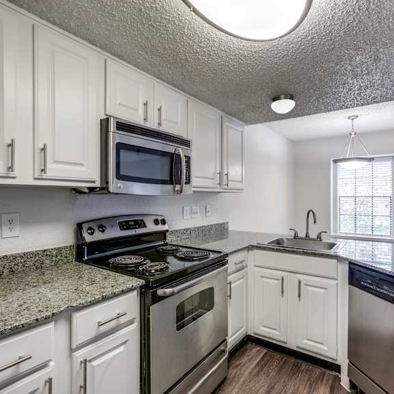 a kitchen with white cabinets and a stainless steel stove