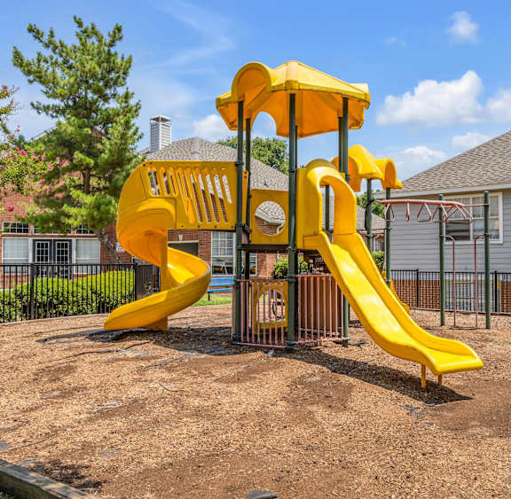 A playground with a yellow slide and a yellow structure. at Villas of Sorrento Apartments, Dallas