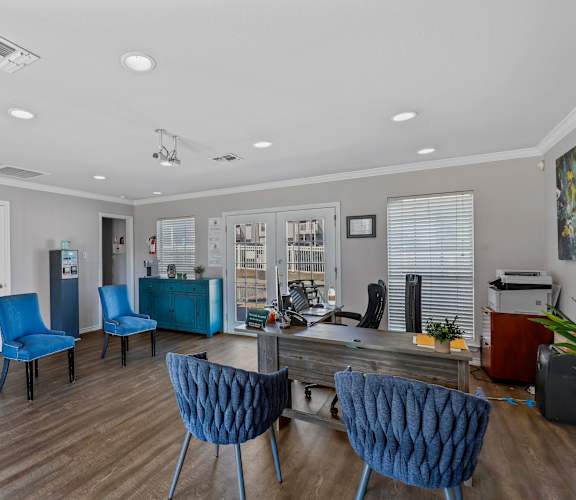 a living room with blue chairs and a desk