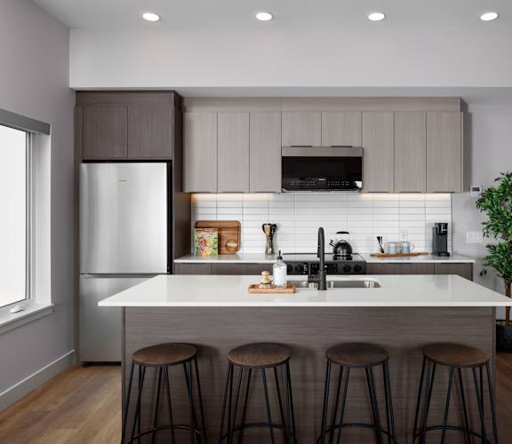 A modern kitchen with a white island and bar stools.