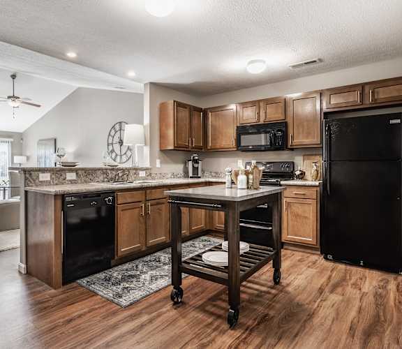 A kitchen with wooden cabinets and a black refrigerator.
