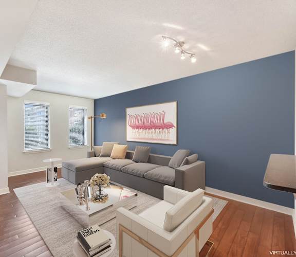 a living room with a blue accent wall and a gray couch at The Saratoga Apartments, Washington, DC 20008