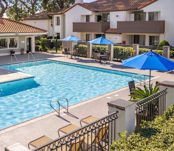 A swimming pool surrounded by blue umbrellas and chairs.