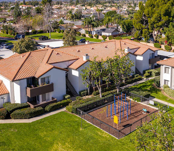 A playground with a swing set is in the front yard of a house.