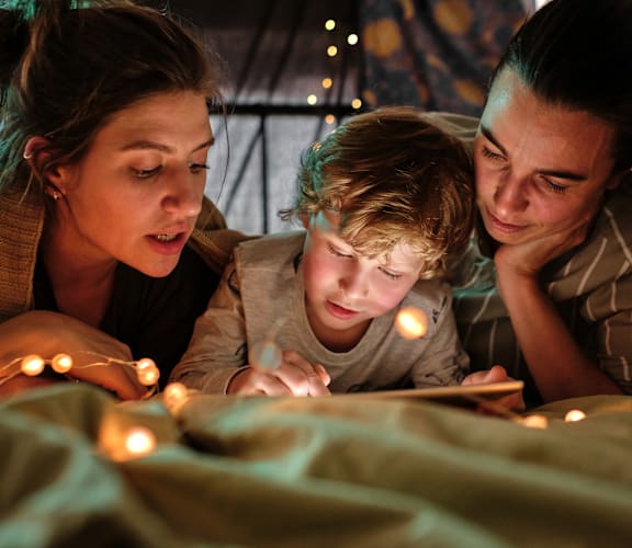 a boy and two women reading a book with lights