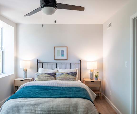 a small bedroom with a bed and a light on the wall