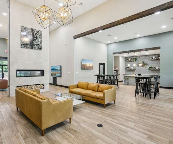 A modern living room with a fireplace and a dining area at Ventana Oaks Apartments, Texas