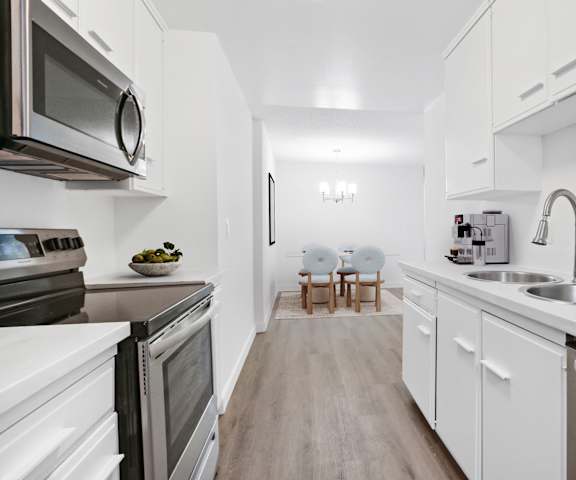 a kitchen with white cabinets and stainless steel appliances and a sink