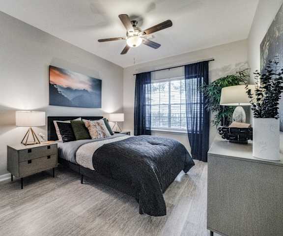an empty bedroom with a ceiling fan and a bed