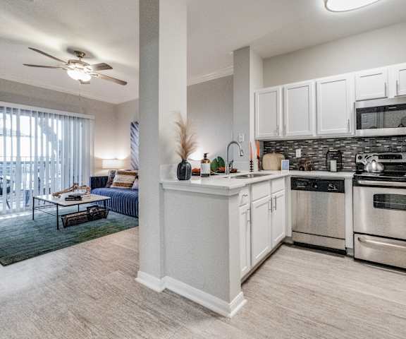 spacious kitchen with stainless steel appliances and white cabinets in an apartment