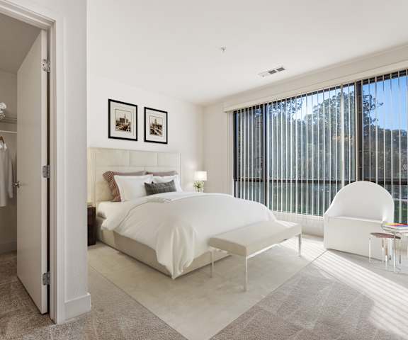 A bedroom with a large bed, a chair, and a wardrobe.