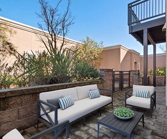 A patio with a couch, a table, and a potted plant.
