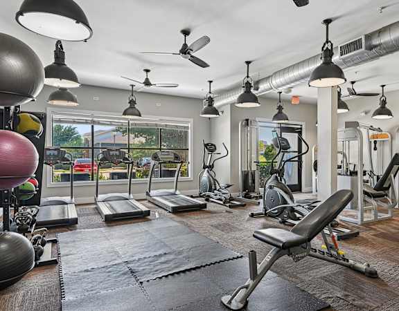 A gym with a variety of equipment including treadmills, weights, and exercise machines.