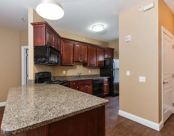A kitchen with granite countertops and wooden cabinets.
