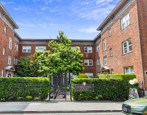 a red brick building with a black gate and a tree in front of it at Carolina Court, Washington, 98109