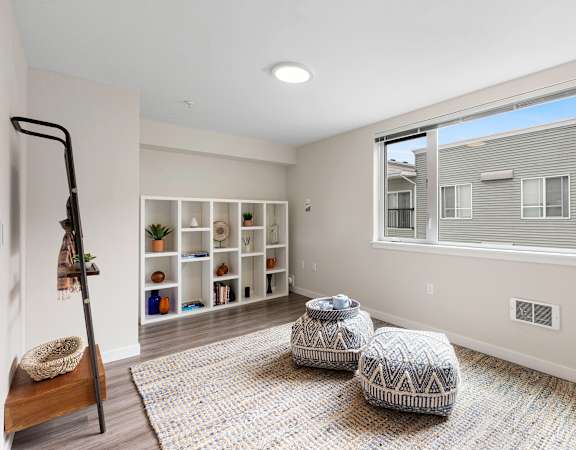 a bedroom with a large window and two stools in the middle of the room at Arabella Apartment Homes in Shoreline, WA