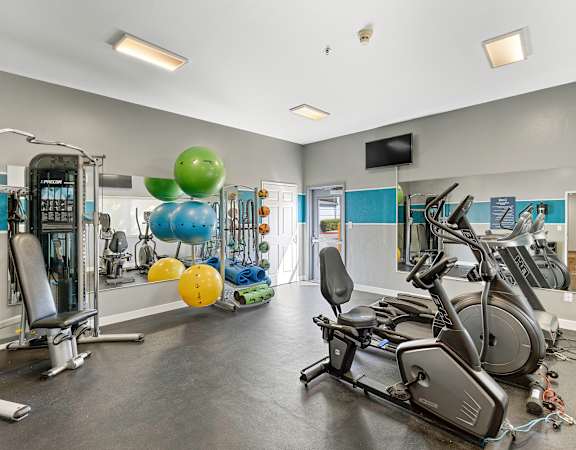 a gym with cardio equipment and weights at Camelot Apartment Homes in Everett