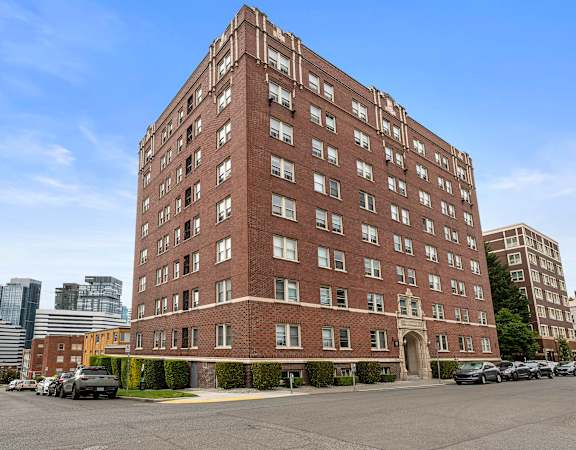 a tall brick building with awnings and a fountain in front of it  at Charbern Apartment Homes, Washington, 98122