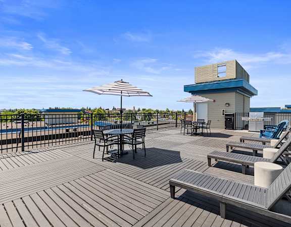 a large deck with a hot tub and tables with umbrellas at Guinevere Apartment Homes, Seattle, WA