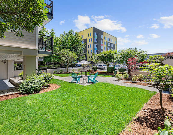 a backyard with green grass and a patio with a table and chairs  at King Arthurs Court, Seattle, Washington