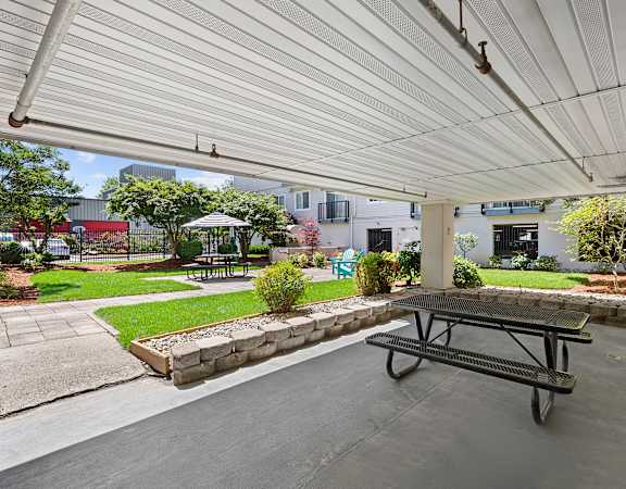 a covered patio with a picnic table and a garden in the background  at King Arthurs Court, Seattle, 98125