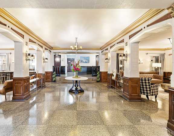 a large lobby with columns and a table with a vase of flowers in the middle