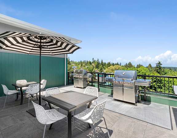 a patio with a table and chairs and a grill at Sedona Apartments in Seattle, WA