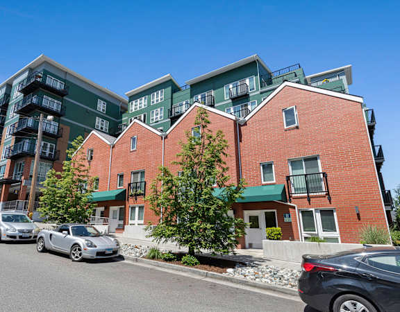 a view from the street of a large apartment complex with cars parked in front of it at Sedona Apartments in Seattle, WA
