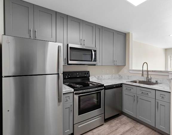 a kitchen with gray cabinets and stainless steel appliances at Excalibur, Washington, 98004