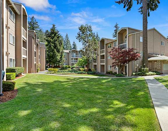 a grassy area with trees and buildings in the background  at Park 210 Apartment Homes, Washington, 98026