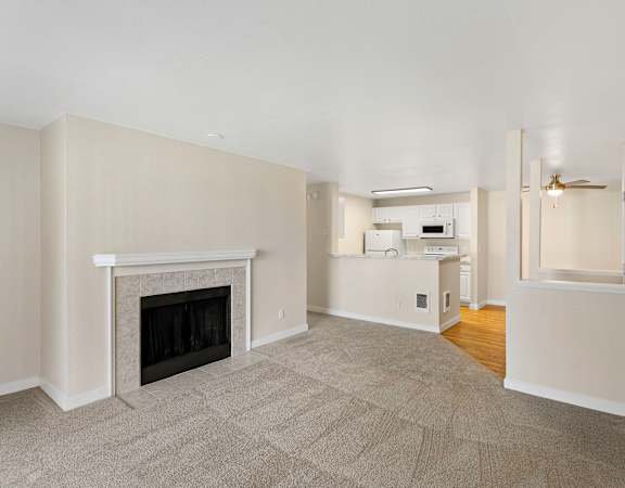 a living room with a fireplace and a kitchen in the background at Serra Vista Apartment Homes, Washington, 98087