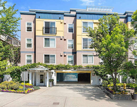 an apartment building with a driveway and trees in front of it at Sir Gallahad, Bellevue, WA