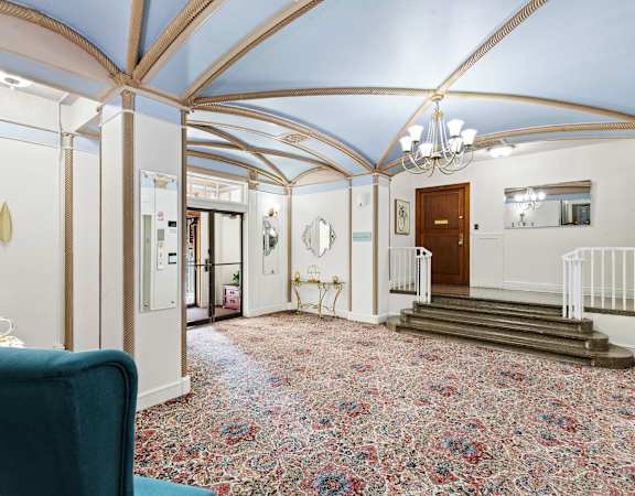 A hallway with a blue chair and a carpeted floor at Stockbridge Apartment Homes, Seattle, 98101
