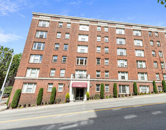 A large brick building with a red awning at the entrance at Stockbridge Apartment Homes, Seattle, 98101