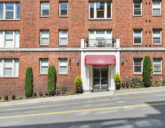 A red brick building with a white entrance and a balcony at Stockbridge Apartment Homes, Seattle, 98101