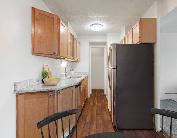 A kitchen with a black refrigerator and wooden cabinets. at Park Towers, St. Louis Park, MN