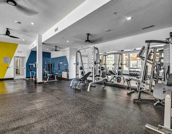 a gym with exercise equipment and a yellow and blue wall at Urban Crest Apartments, San Antonio, TX, 78209