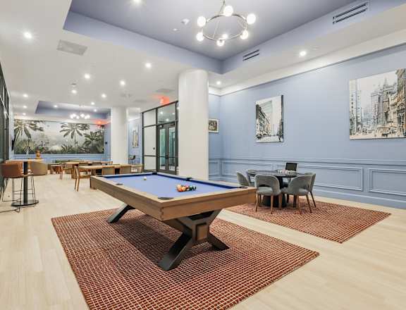 A pool table is in the middle of a room with a blue wall and a painting of a cityscape. at LiveWell Apartments, Pittsburgh, PA, 15222