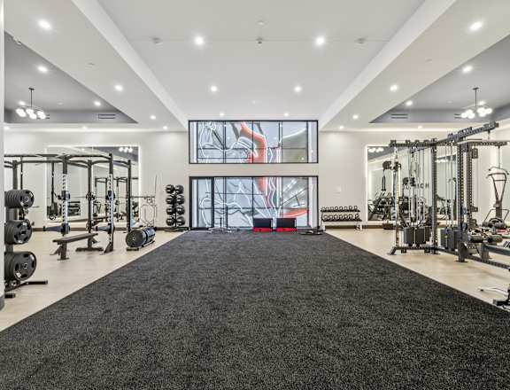 A spacious gym with a variety of equipment and a large mirror on the wall. at LiveWell Apartments, Pittsburgh, PA, 15222