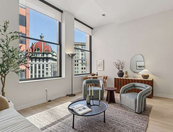 A living room with a large window and a view of a building with a red roof. at LiveWell Apartments, Pittsburgh, PA, 15222