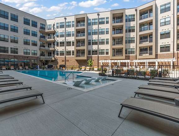 an outdoor pool with chaise lounge chairs and a building in the background  at The Griffin Royal Oak, Royal Oak, Michigan