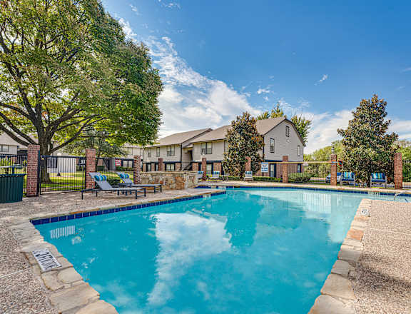 A large swimming pool surrounded by a fence and trees.