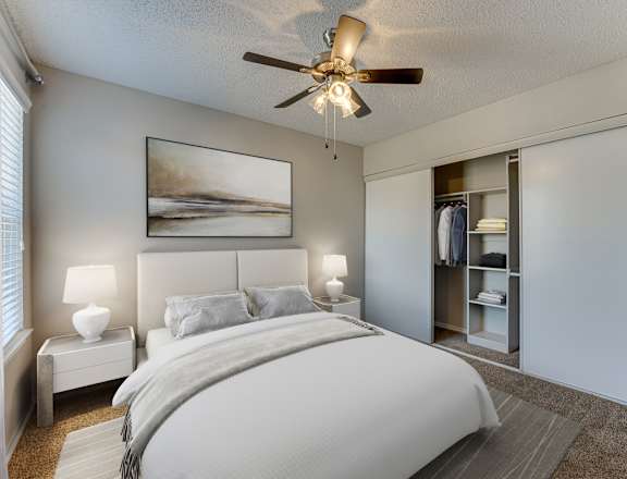 A bedroom with a large bed and a ceiling fan.