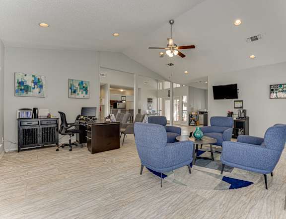 A living room with a blue chair and a ceiling fan.