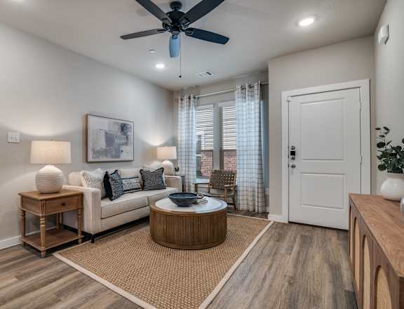 A living room with a white couch, a round coffee table, and a ceiling fan.